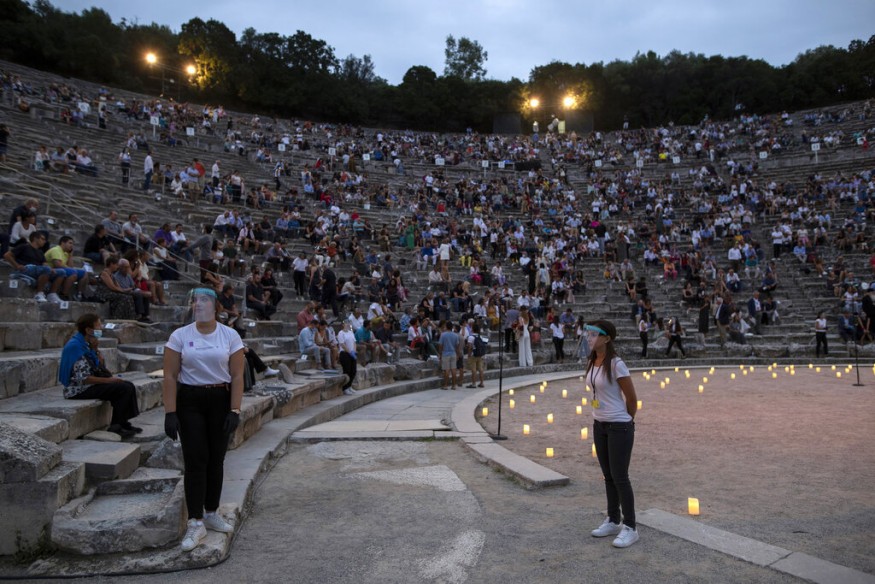 Stewards wearing surgical gloves and plastic visors stands as spectators take their seats at the ancient theatre of Epidaurus, Greece. (Image: AP)